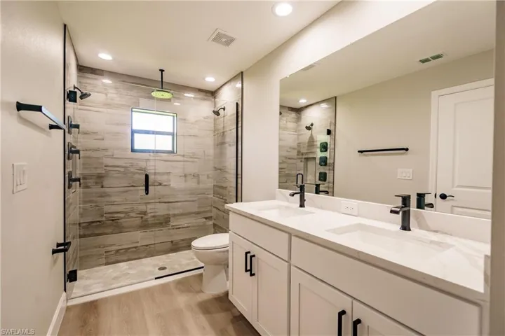Bathroom with vanity, hardwood / wood-style flooring, toilet, and an enclosed shower