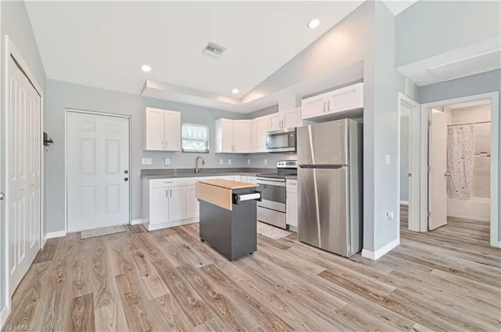Kitchen featuring white cabinets, light wood-type flooring, and appliances with stainless steel finishes