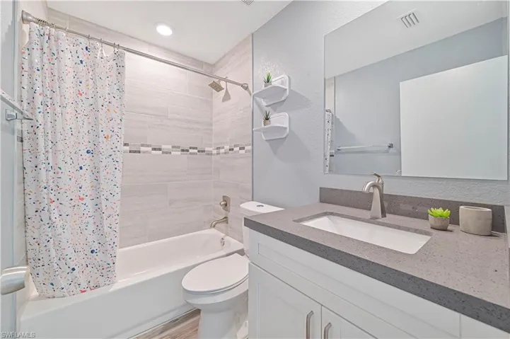 Full bathroom with shower / bath combination with curtain, wood-type flooring, toilet, and vanity