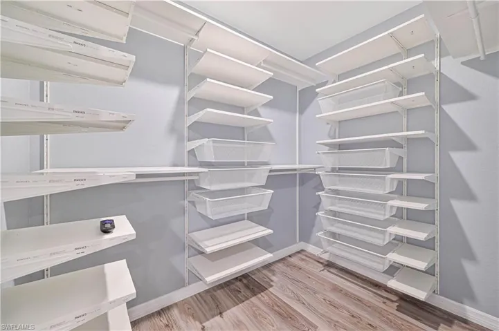 Walk in closet with hardwood / wood-style flooring