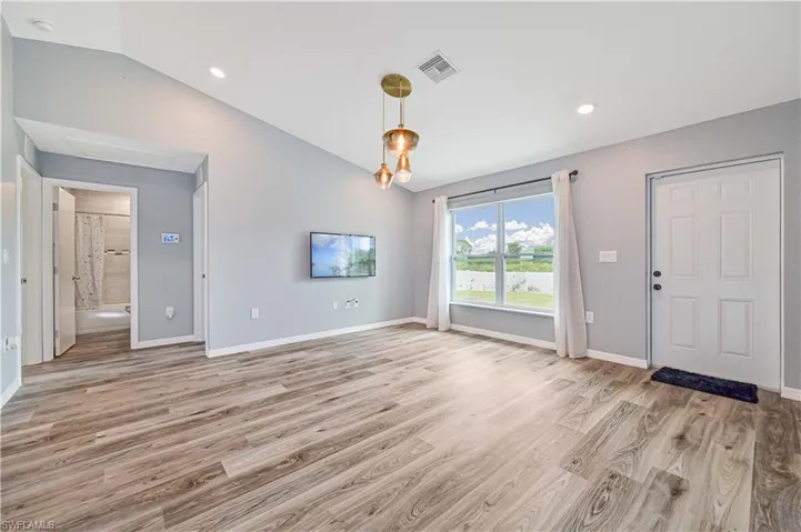 Unfurnished living room featuring light hardwood / wood-style floors and vaulted ceiling