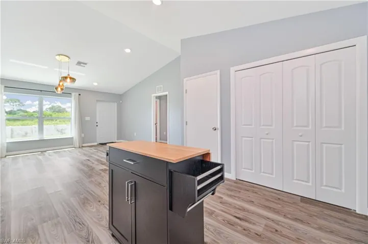 Kitchen with light hardwood / wood-style floors and vaulted ceiling