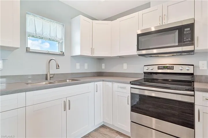 Kitchen featuring appliances with stainless steel finishes, sink, white cabinets, and light hardwood / wood-style floors