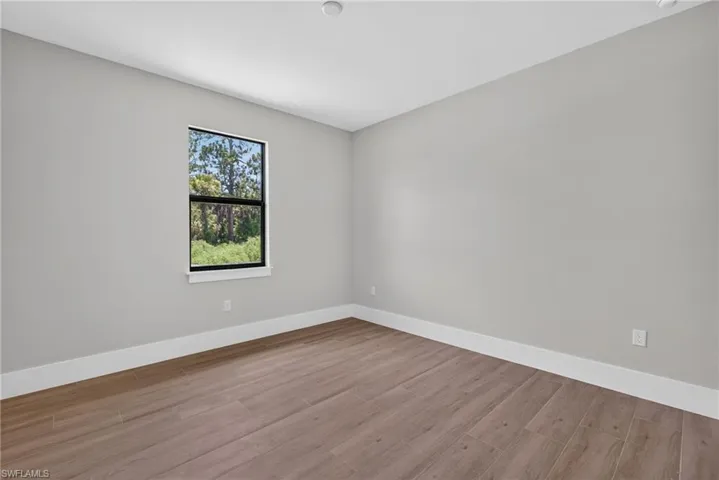 Room with wood-finish flooring, light gray walls, and white baseboards