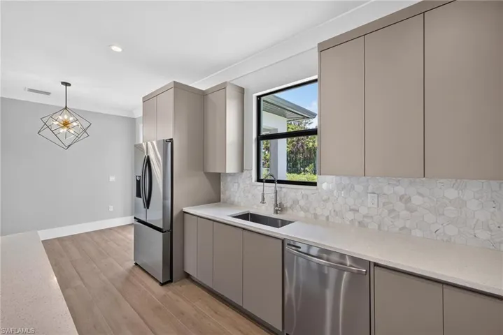 Kitchen featuring neutral-toned flat-panel cabinetry, stainless steel appliances, and light-toned countertops