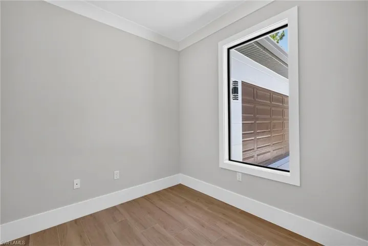 Neutral wall paint with crown molding and wood-finish flooring