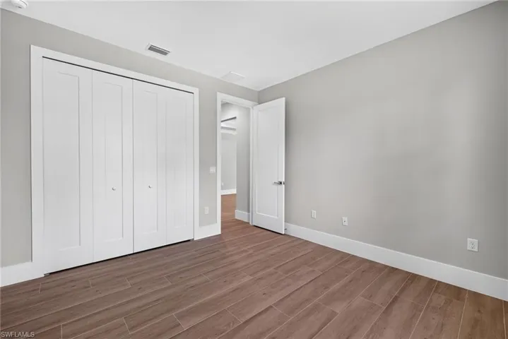 Spacious room featuring wood-finish flooring, light grey walls, and white trim
