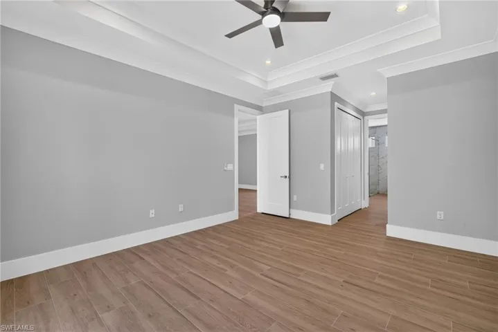 Spacious room featuring wood-finish flooring, light grey walls, and white trim