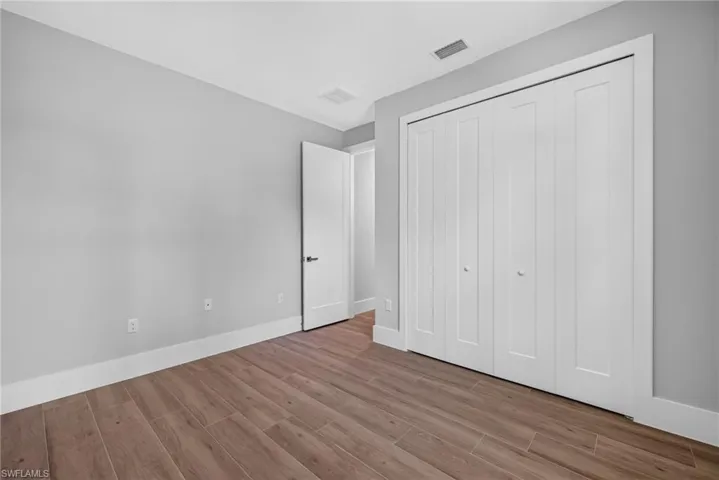 Room featuring wood-finish flooring, light grey walls, and white trim
