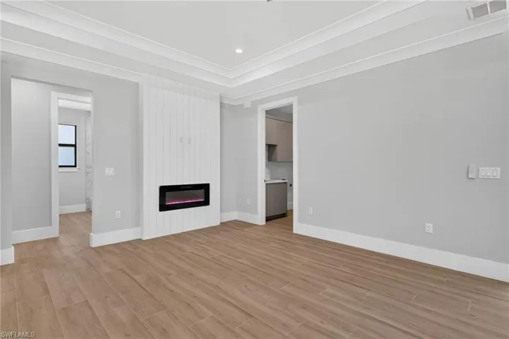 Living area featuring wood-finish flooring, a contemporary electric fireplace with a white shiplap-style surround, and recessed lighting