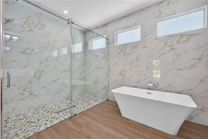 Contemporary bathroom featuring a freestanding soaking tub and a spacious walk-in shower with pebble tile flooring