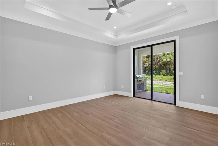 Spacious room featuring wood-finish flooring and a tray ceiling with recessed lighting