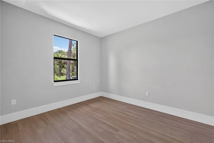Room featuring light gray walls, white baseboards, and wood-finish flooring