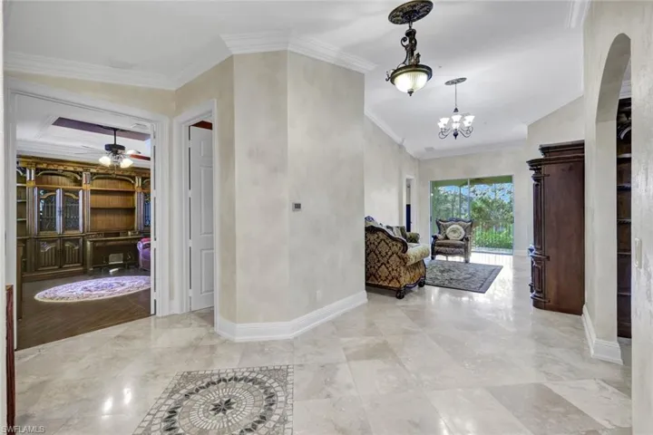 Hall with crown molding and a chandelier