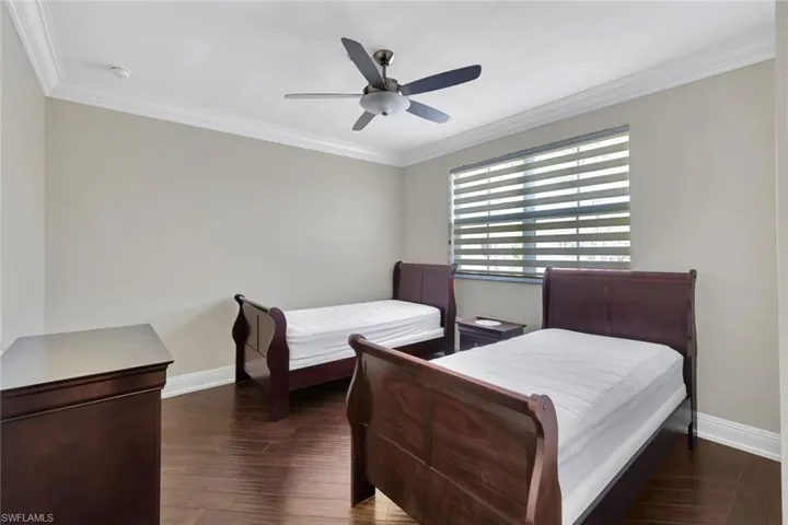 Bedroom featuring dark wood finished floors, crown molding, and ceiling fan