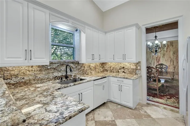 Kitchen with white cabinets, a chandelier, white appliances, ornamental molding, and light stone counters