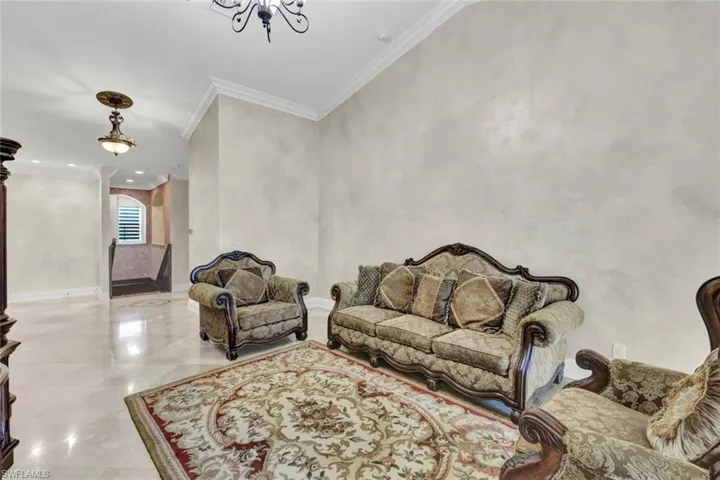 Living room with ornamental molding and a chandelier