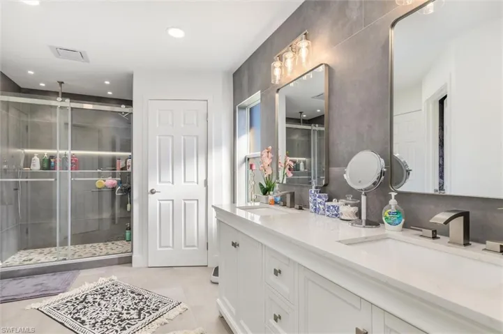 Full bath featuring double vanity, a shower stall, and recessed lighting