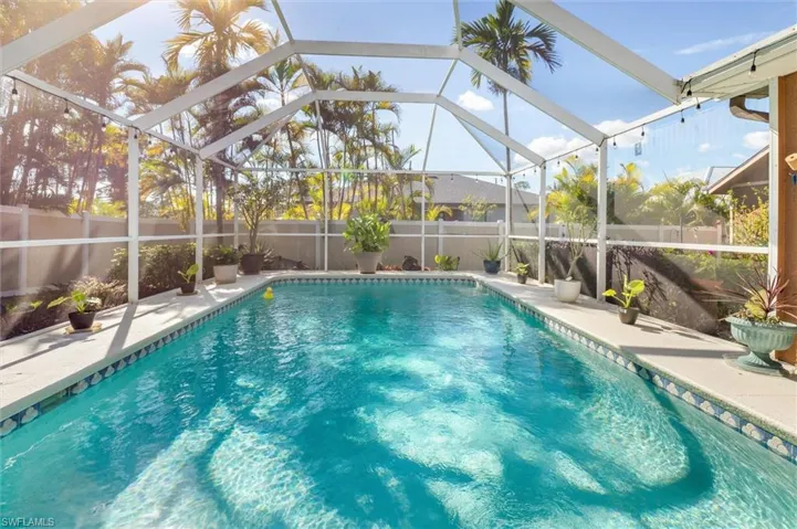 View of pool with glass enclosure, a fenced backyard, a sunroom, and a patio