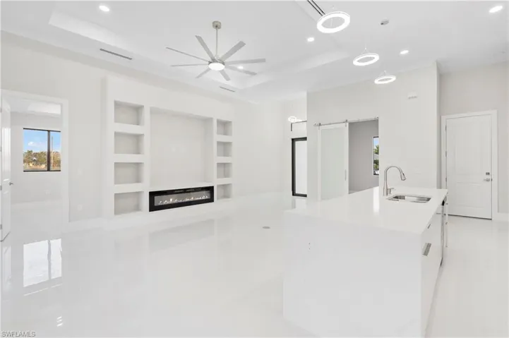 Kitchen with a kitchen island with sink, sink, a tray ceiling, and a barn door