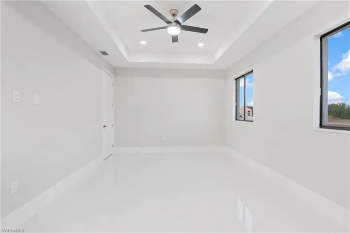 Unfurnished room with a raised ceiling and ceiling fan