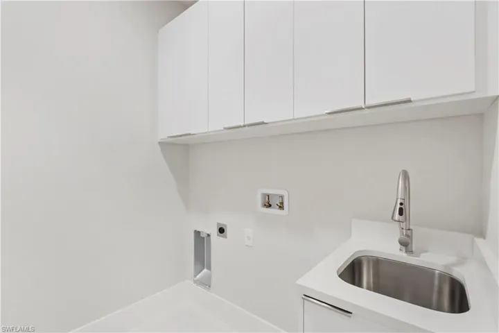 Laundry area featuring sink, hookup for a washing machine, cabinets, and hookup for an electric dryer