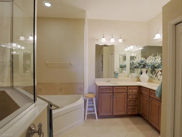 Full bath featuring vanity, light tile patterned flooring, and a bath