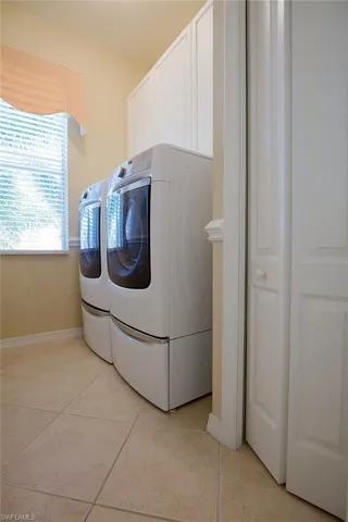 Laundry room featuring washer and clothes dryer, cabinet space, and light tile patterned floors