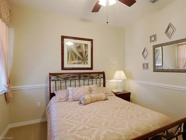 Carpeted bedroom featuring ceiling fan and multiple windows