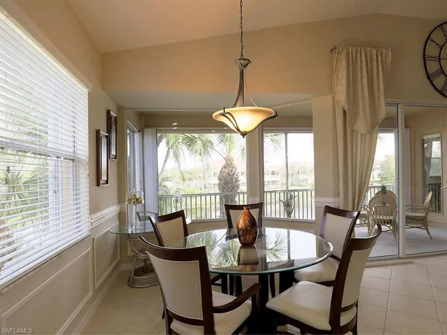 Dining room with light tile patterned floors, plenty of natural light, and vaulted ceiling