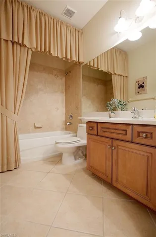 Bathroom with shower / bathtub combination with curtain, vanity, and light tile patterned flooring