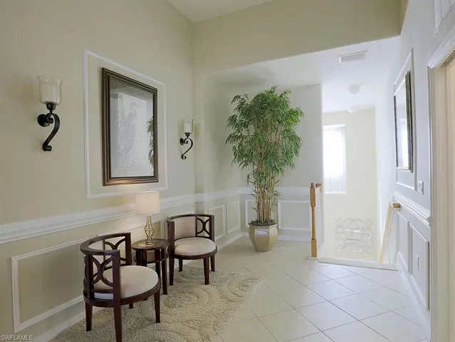 Sitting room with a decorative wall, light tile patterned floors, wainscoting, and an upstairs landing