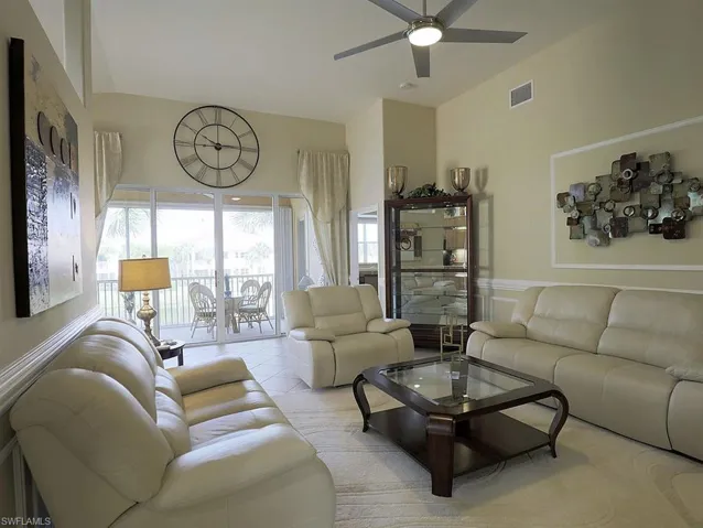 Living area with light tile patterned floors, ceiling fan, and a high ceiling