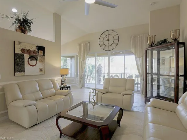 Living room with ceiling fan, light tile patterned floors, and vaulted ceiling