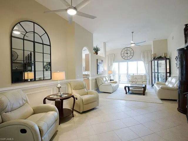 Living area featuring a decorative wall, a wainscoted wall, ceiling fan, lofted ceiling, and light tile patterned floors
