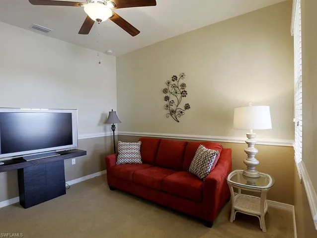 Carpeted living area with ceiling fan and baseboards  Pullout couch