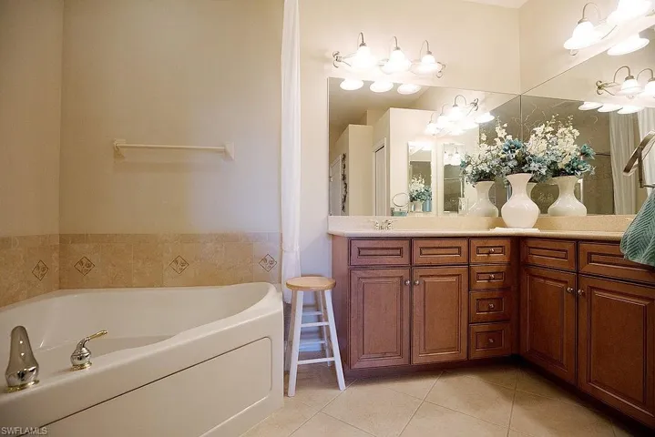 Full bath featuring a garden tub, double vanity, and light tile patterned floors