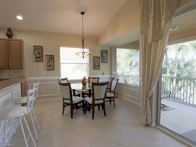 Dining room featuring light tile patterned floors, a decorative wall, and a wainscoted wall