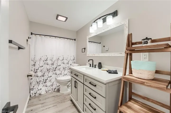 1st Floor Bathroom featuring a shower with curtain, vanity, and light wood finished floors- Virtually Edited Image