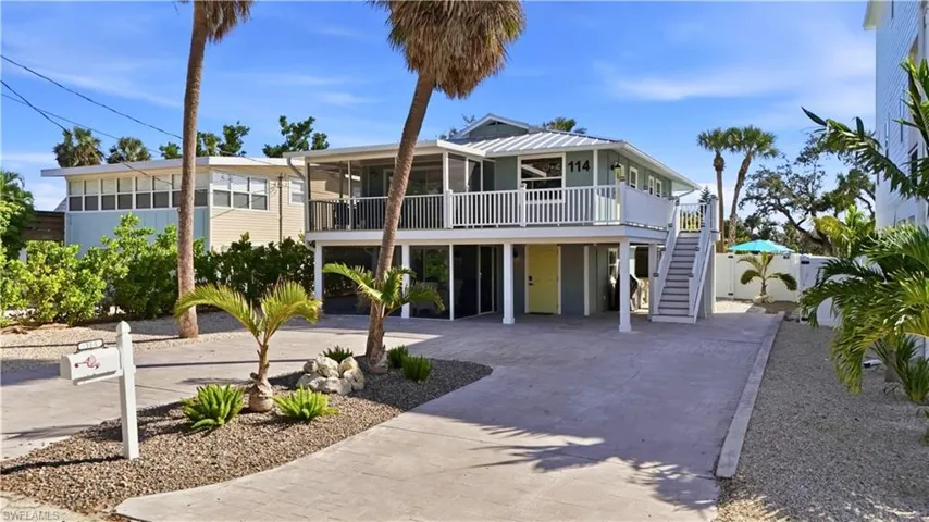 Coastal inspired home featuring a carport, decorative driveway, stairway, and a deck- Virtually Edited Image
