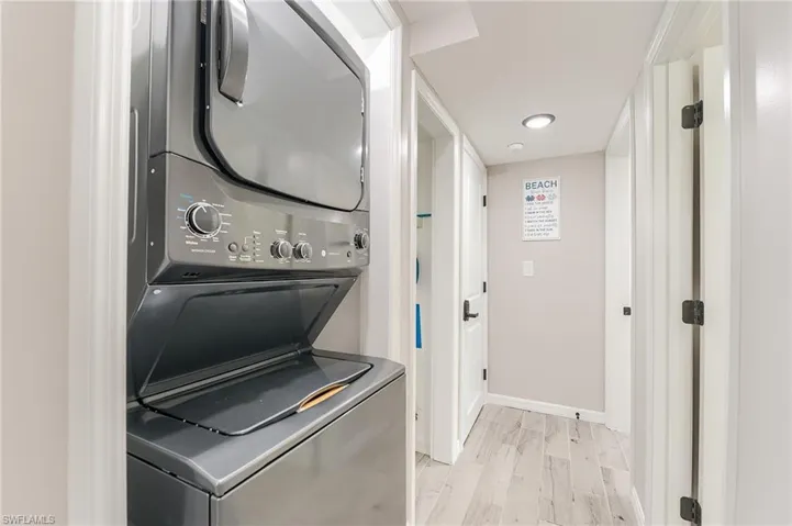 1st Floor Laundry room featuring stacked washer and clothes dryer and light wood-style flooring- Virtually Edited Image