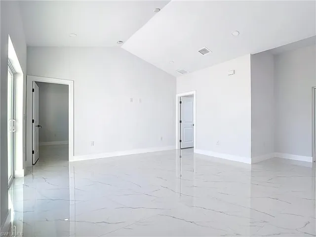 Unfurnished room with light marble finish floors, vaulted ceiling, and recessed lighting