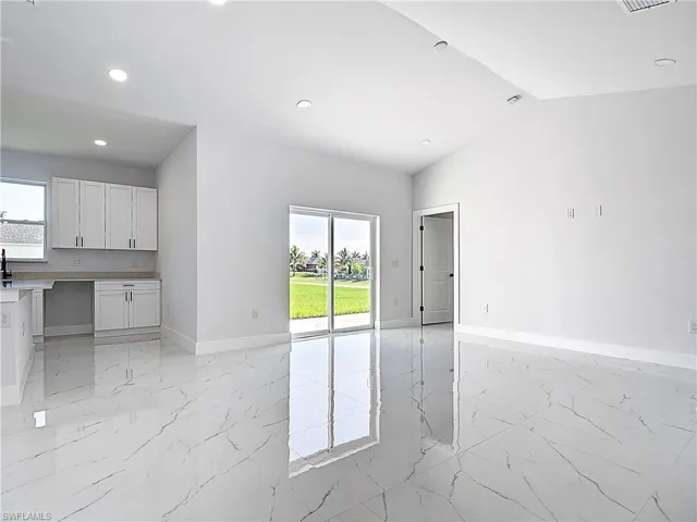 Unfurnished living room featuring light marble finish flooring, recessed lighting, and lofted ceiling