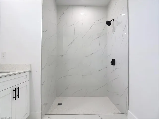 Bathroom with vanity and a marble finish shower