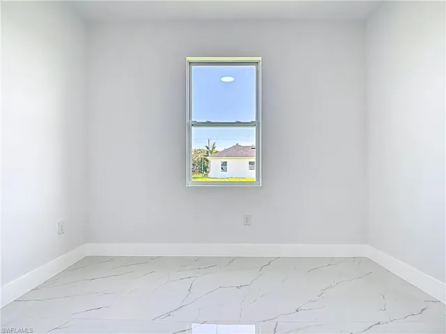 Empty room featuring light marble finish floors and baseboards