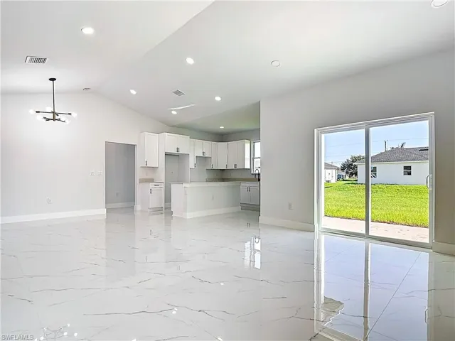 Unfurnished living room featuring light marble finish floors, recessed lighting, lofted ceiling, and a chandelier