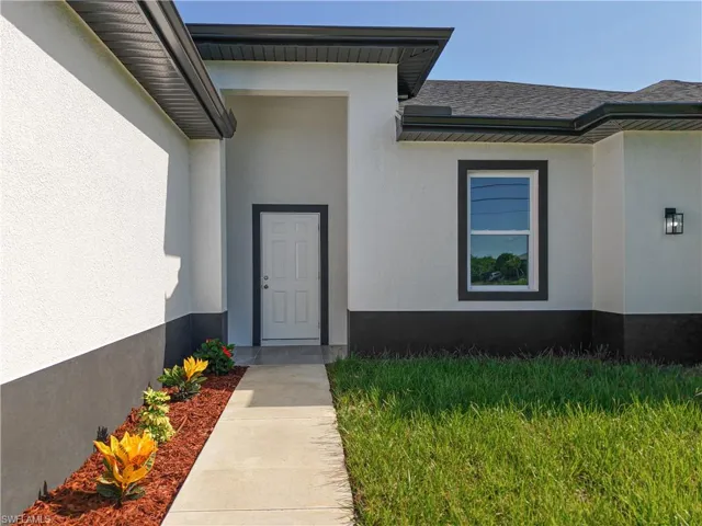 View of exterior entry with stucco siding and roof with shingles