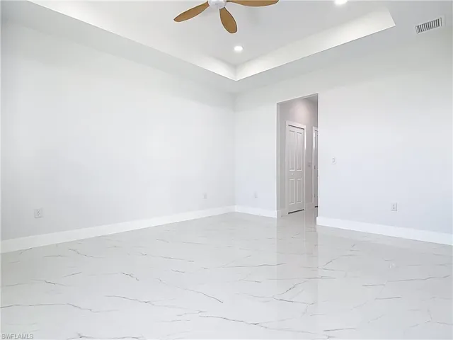 Spare room with light marble finish floors, a raised ceiling, a ceiling fan, and recessed lighting