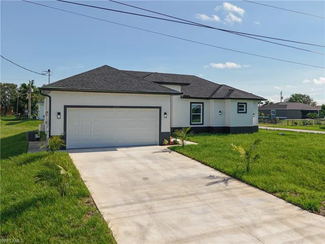 View of front facade with stucco siding, a front lawn, a shingled roof, and concrete driveway