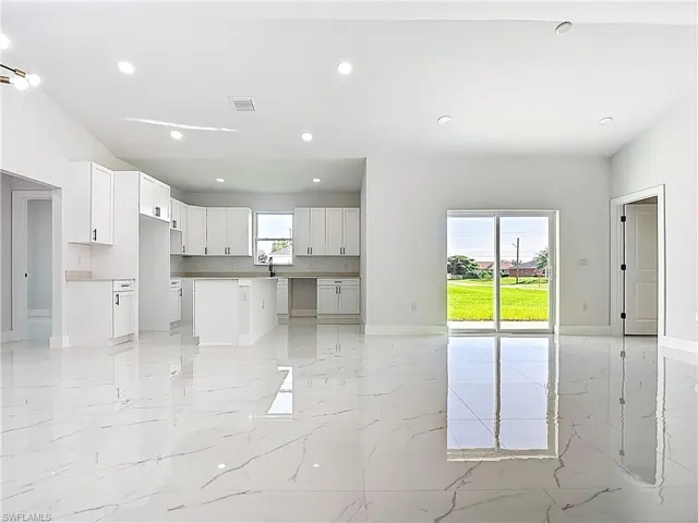 Kitchen featuring light marble finish floors, recessed lighting, open floor plan, white cabinets, and a center island
